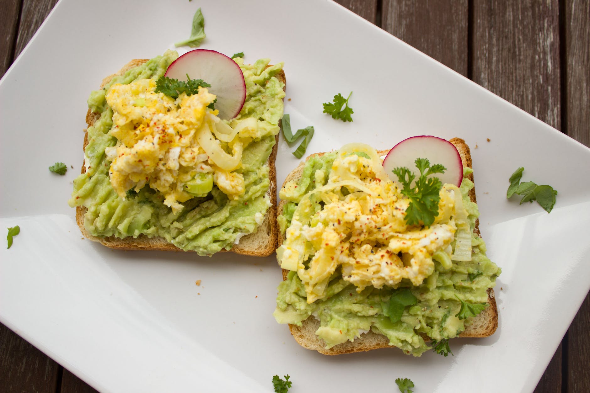 bread with guacamole parsley leaves onions and eggs on platter